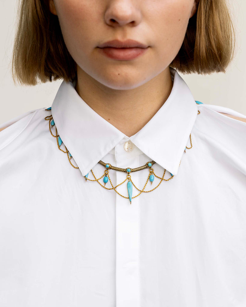 This is a rare example of an elaborate 19th-century collar necklace. Natural Persian turquoise stones are cut in the shapes of amphoras, with rose-cut diamonds set at the sharp tip of every setting. The necklace is made of 18k gold and was made in England, circa 1860. The necklace is being worn with a button up collar shirt. 