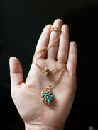 Early Victorian era turquoise padlock locket in 15k gold. It is in the form of a shell with Persian turquoise and a glazed compartment.&nbsp; English in origin. Circa 1840. Hanging on an antique 15k gold turquoise beaded ball chain. In the palm of someone's hand to show the scale of the piece. 