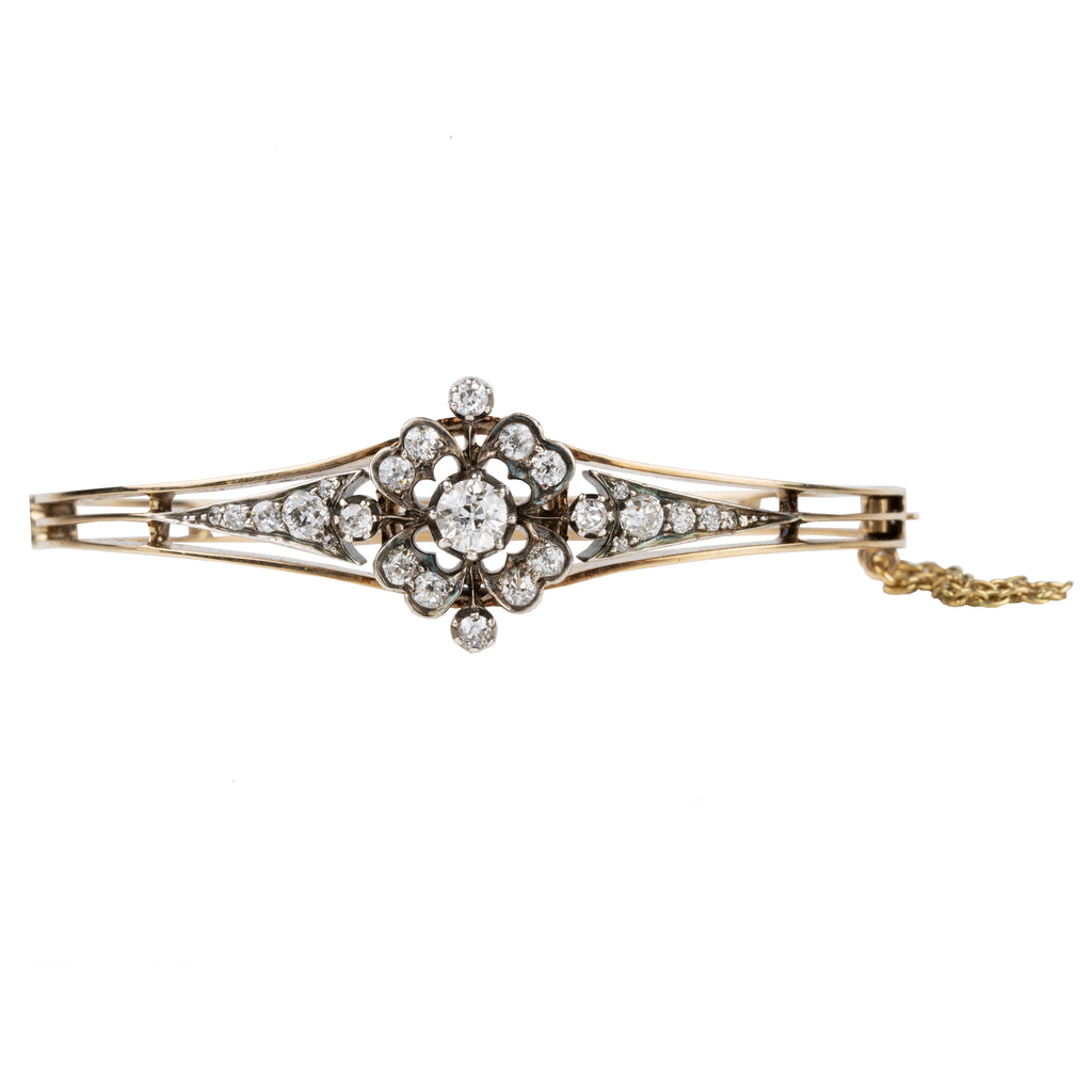 Late 19th century floral diamond bangle bracelet, in silver topped gold. The center diamond is an old mine cut diamond, approximately .75 carats, flanked by additional old mine cut diamonds. English in origin. Circa 1890. Front View. 