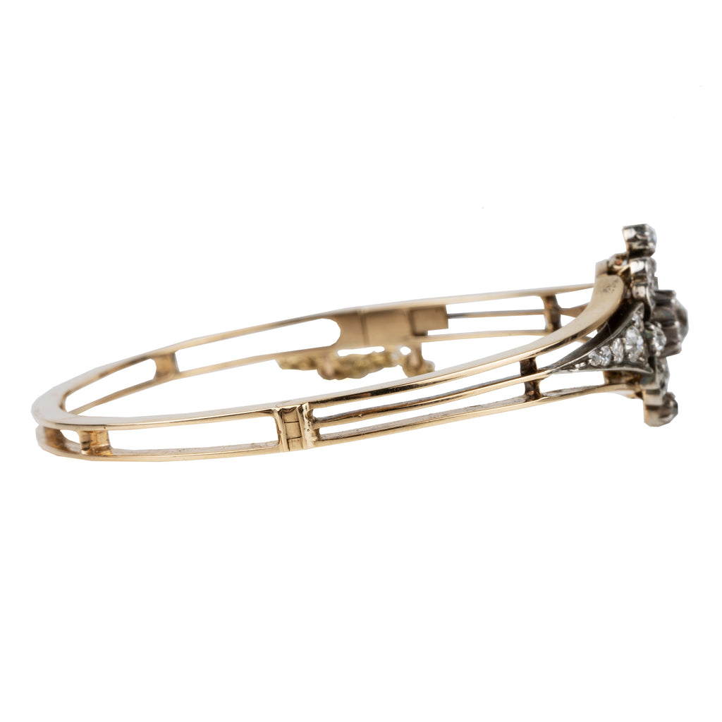 Late 19th century floral diamond bangle bracelet, in silver topped gold. The center diamond is an old mine cut diamond, approximately .75 carats, flanked by additional old mine cut diamonds. English in origin. Circa 1890. Side view. 