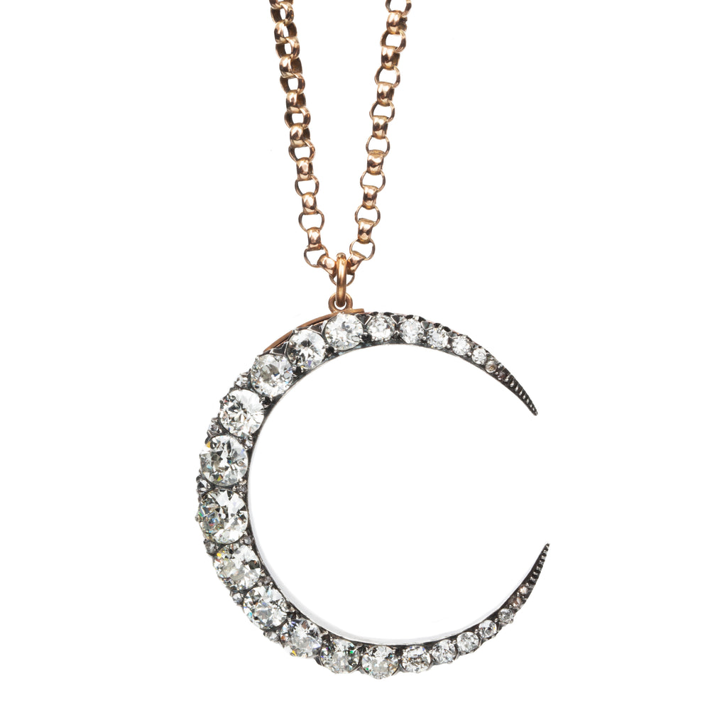 A slender arc of light executed in glittering old mine cut diamonds. Crafted in a silver-topped gold setting this piece has been masterfully constructed to function as a brooch and a pendant with the original fixtures still intact. Approximately 7.20 carats in total diamond weight. English in origin. Front view, hanging on a chain. 